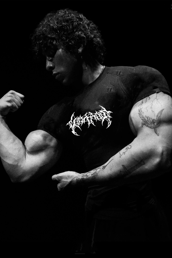 Muscular man flexing his arm wearing a black t-shirt with white text on a dark background