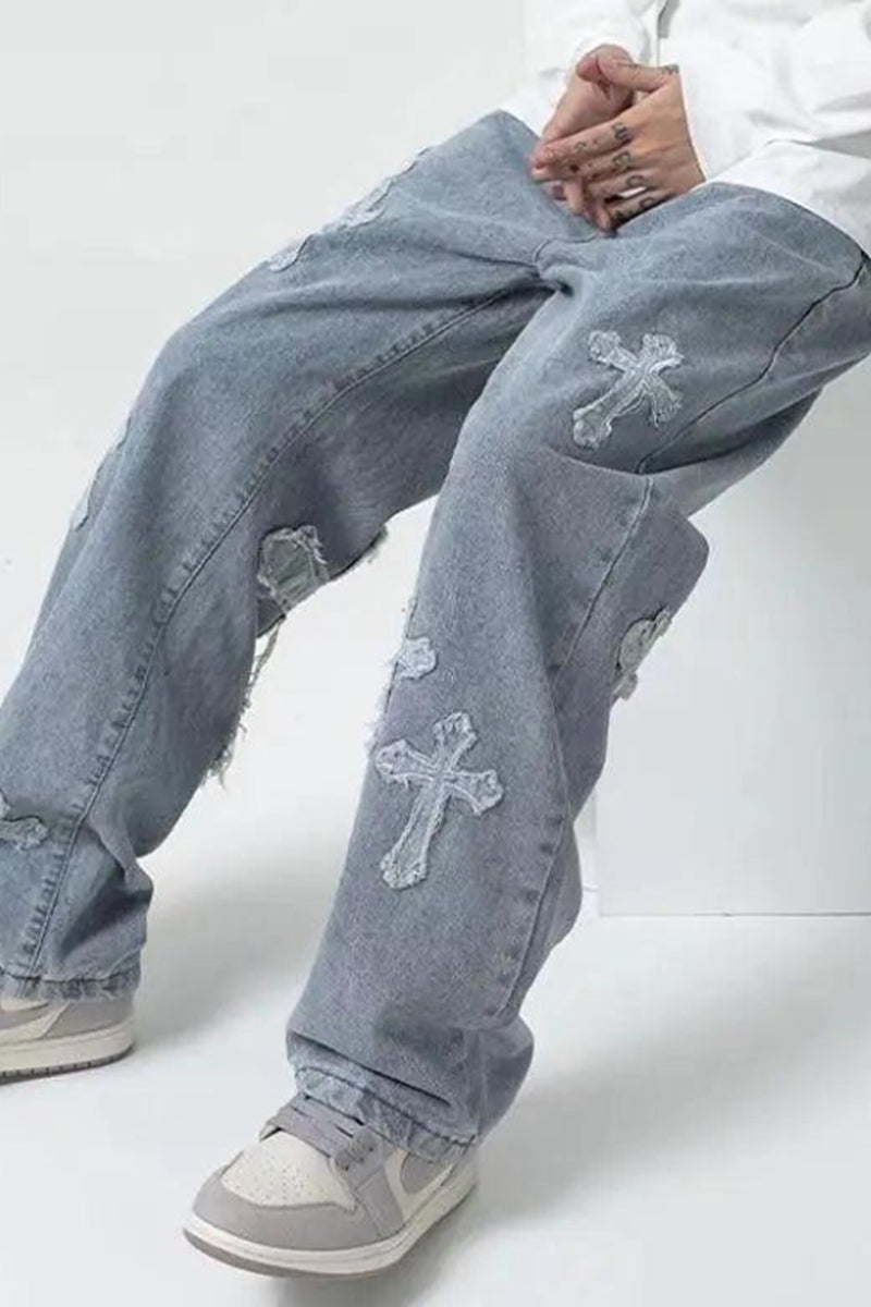 Light blue jeans with cross patterns worn by a person on a white background