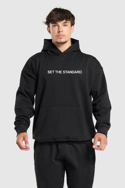 Oversized hoodie featuring 'Set the Standard' text, designed for comfort and style with a relaxed fit and adjustable drawstring hood.
